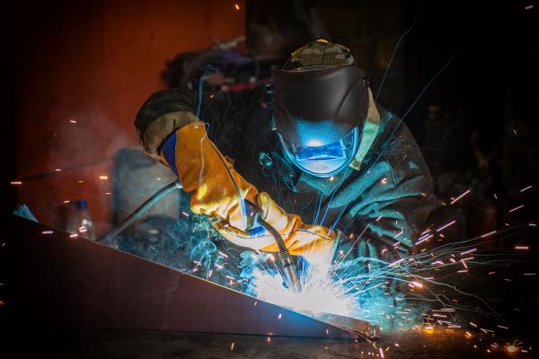 welder working on repair in fabrication shop